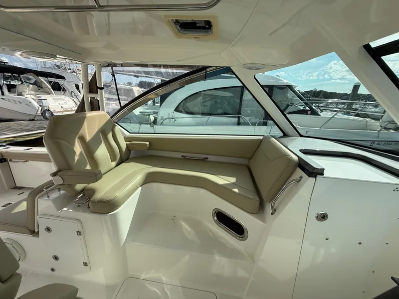 Slide: The Image of 2017 Pursuit DC 325 Dual Console interior with beige seating and marina view. - 38