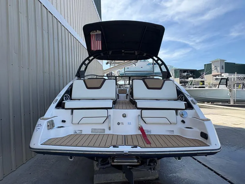 Slide: The Image of 2021 Yamaha Boats 252SE, rear view, docked, showcasing seating and deck design. - 2