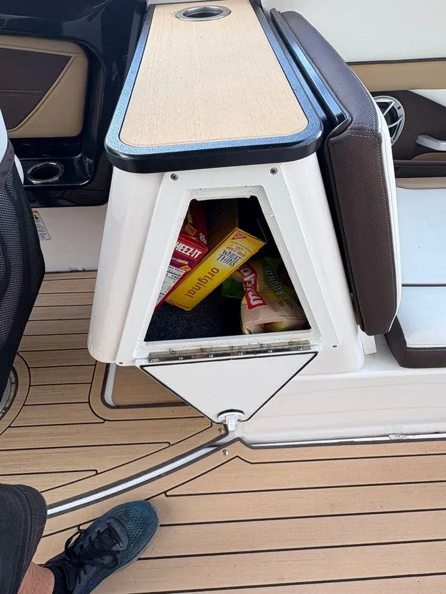 Slide: The Image of 2021 Yamaha Boats 252SE interior storage with snacks on a wooden deck. - 20