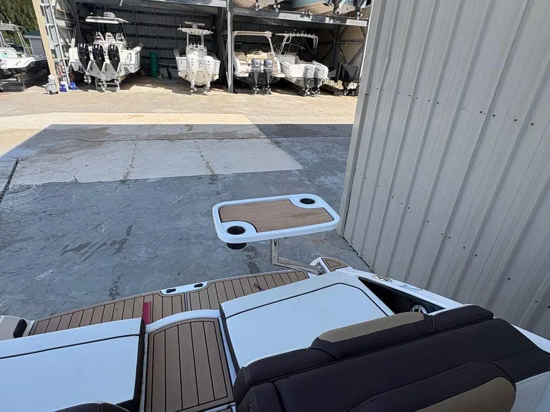 Slide: The Image of 2021 Yamaha Boats 252SE with swim platform and table, docked near other boats. - 5