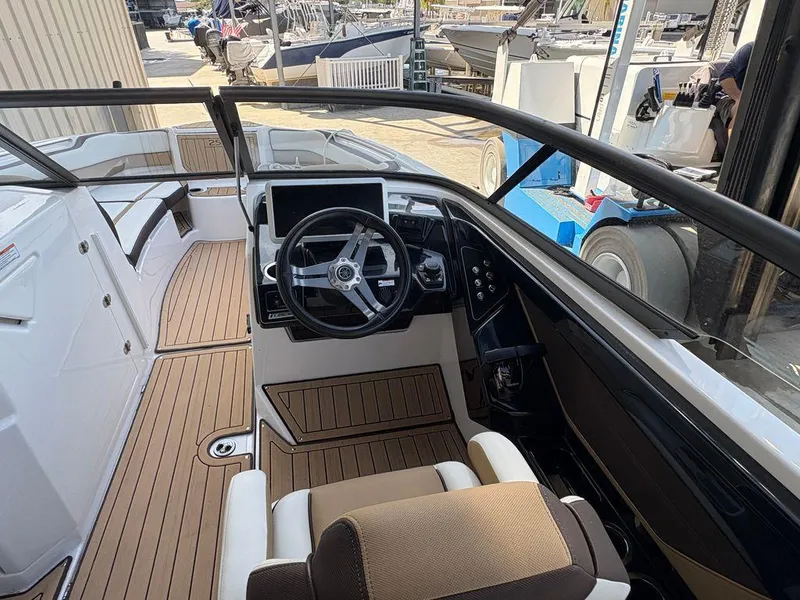 Slide: The Image of 2021 Yamaha Boats 252SE cockpit with modern steering and seating, docked at marina. - 7