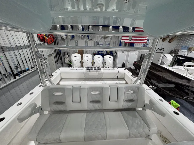 Slide: The Image of 2024 Contender 44 ST boat interior with seating, fishing rods, and engines in a showroom. - 17