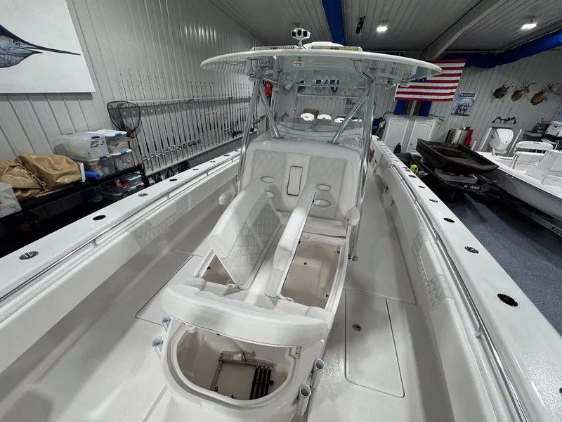 Slide: The Image of 2024 Contender 44 ST boat interior with white seating, fishing rods, and American flag in showroom. - 26