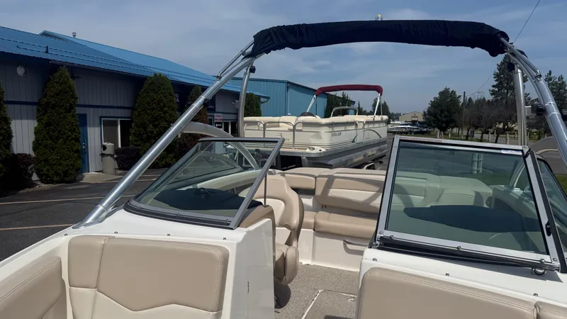 Slide: The Image of 2011 Chaparral 206 SSi boat with beige interior, parked near blue-roofed building. - 16