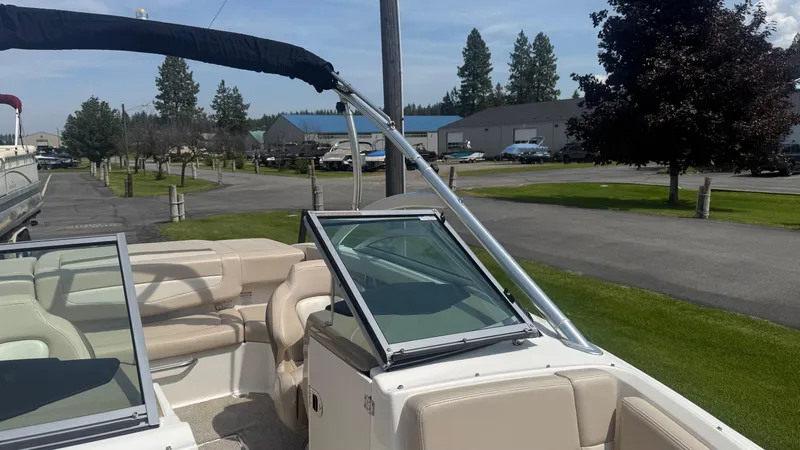 Slide: The Image of 2011 Chaparral 206 SSi boat with beige interior, parked outdoors near trees and buildings. - 17