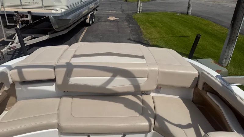 Slide: The Image of 2011 Chaparral 206 SSi boat interior with beige seating and nearby trailer. - 19