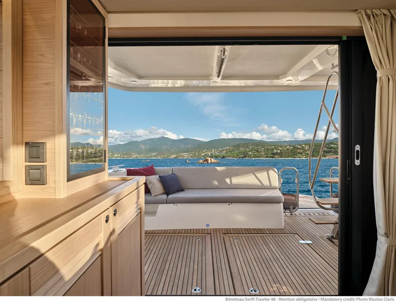 Slide: The Image of Interior view of 2026 Beneteau Swift Trawler 48, showcasing elegant wood finish and ocean backdrop. - 12