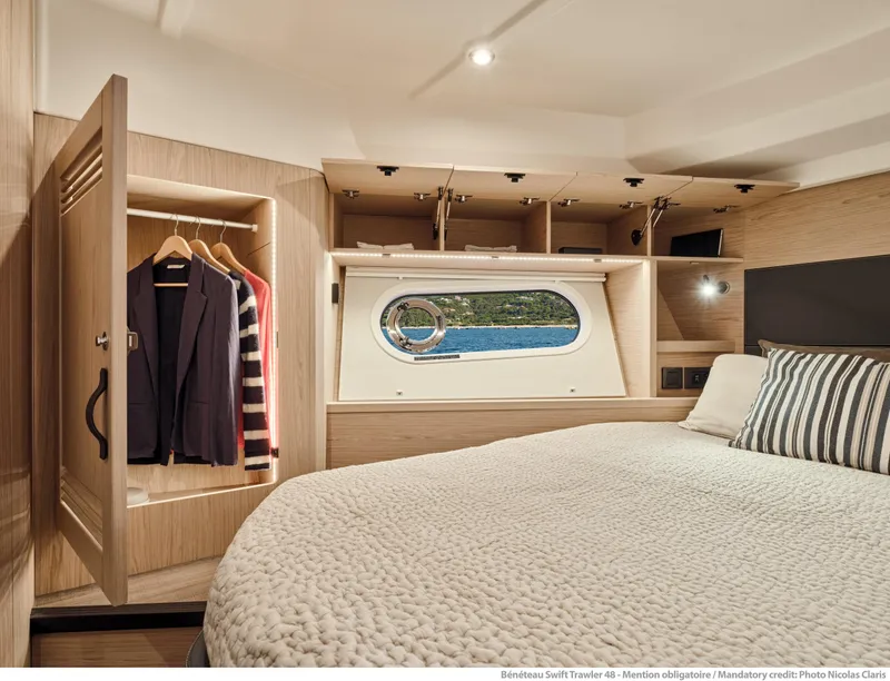 Slide: The Image of Luxurious cabin interior of 2026 Beneteau Swift Trawler 48 with wardrobe and porthole view. - 24