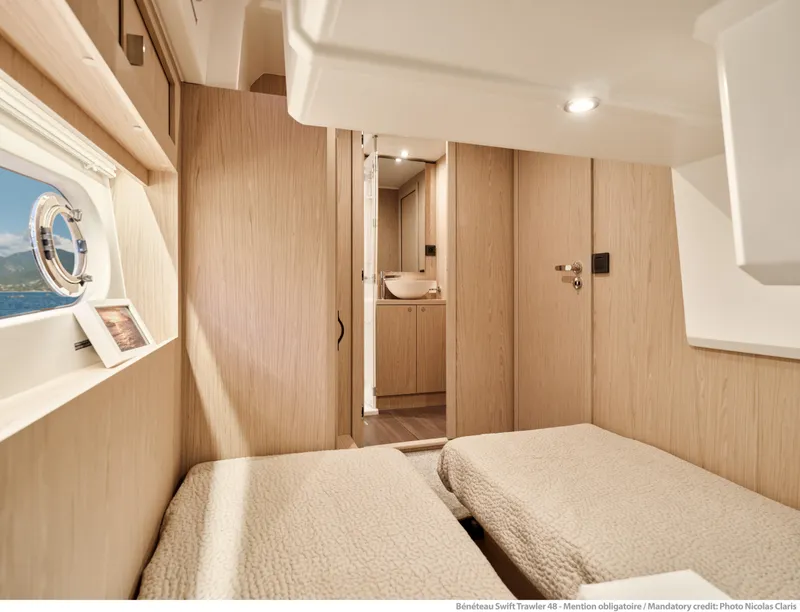 Slide: The Image of Interior of 2026 Beneteau Swift Trawler 48, featuring twin beds and modern wood finish. - 27