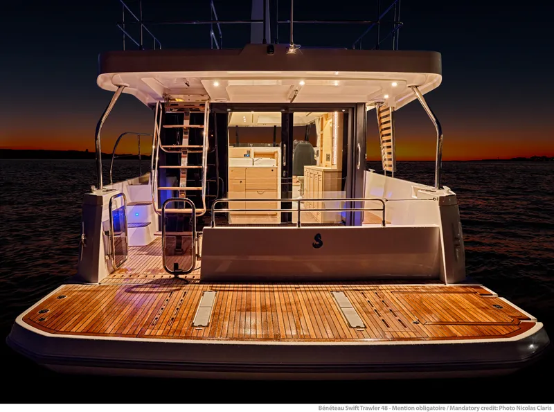 Slide: The Image of 2026 Beneteau Swift Trawler 48 at sunset, showcasing elegant deck and interior lighting. - 28
