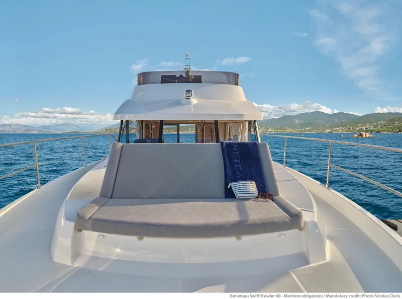 Slide: The Image of 2026 Beneteau Swift Trawler 48 on open sea, showcasing deck seating and scenic ocean view. - 6