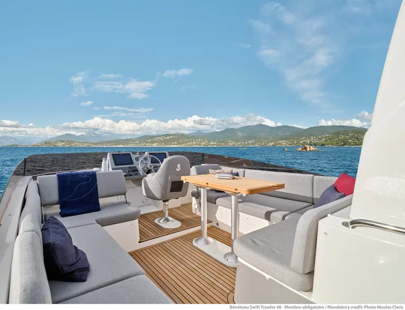 Slide: The Image of 2026 Beneteau Swift Trawler 48 deck with seating, table, and ocean view. - 8