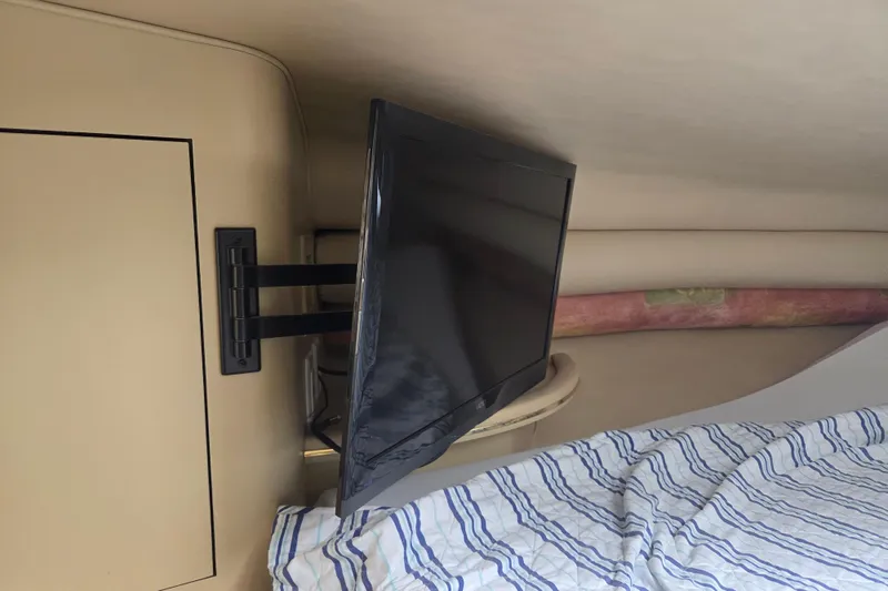 Slide: The Image of Interior of 1998 Sea Ray 310 Sundancer with mounted TV and striped bedding. - 12