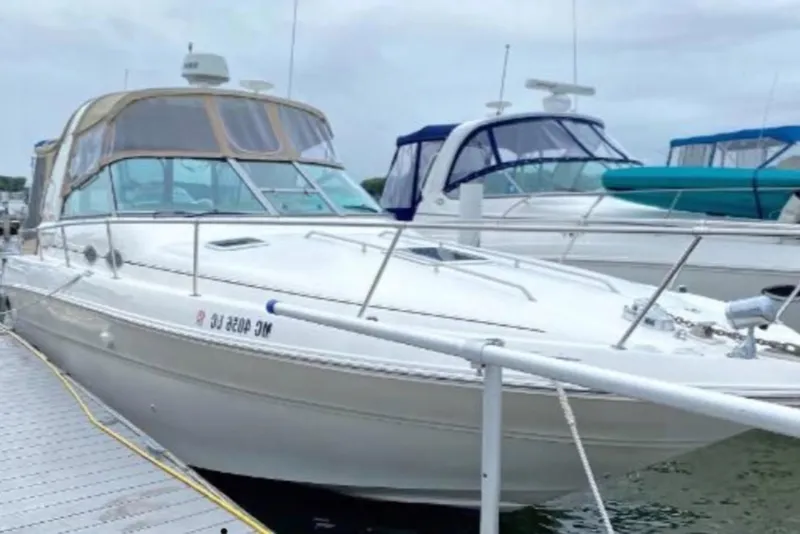 Slide: The Image of 1998 Sea Ray 310 Sundancer docked at marina, featuring sleek design and spacious cabin. - 2