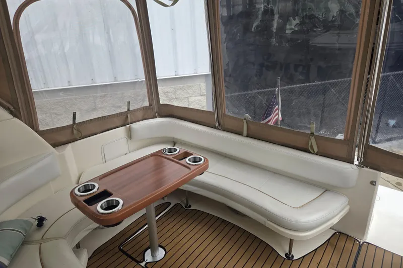 Slide: The Image of 1998 Sea Ray 310 Sundancer interior with seating and wooden table, featuring cup holders. - 7