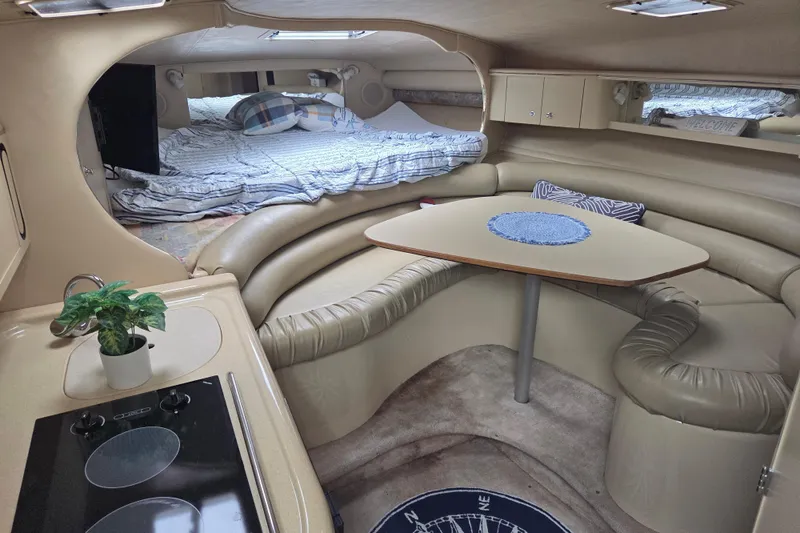 Slide: The Image of 1998 Sea Ray 310 Sundancer cabin interior with cozy seating, table, and kitchenette. - 9