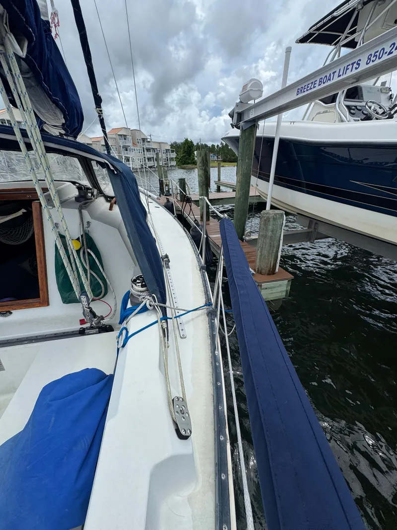 Slide: The Image of 1986 C&C 29 sailboat docked beside a boat lift under cloudy skies. - 14