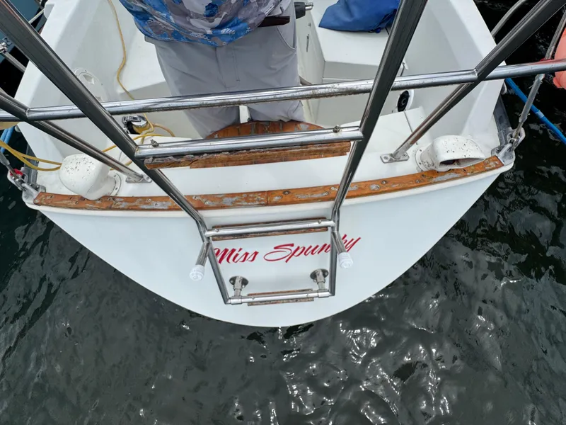 Slide: The Image of 1986 C&C 29 sailboat stern with ladder, named "Miss Spunky," docked on water. - 2