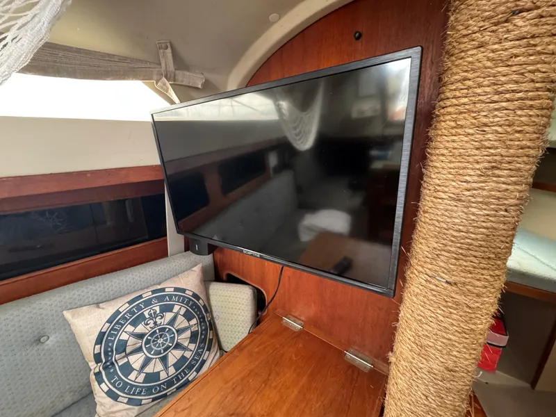 Slide: The Image of Interior of 1986 C&C 29 sailboat with mounted TV and nautical-themed pillow. - 23