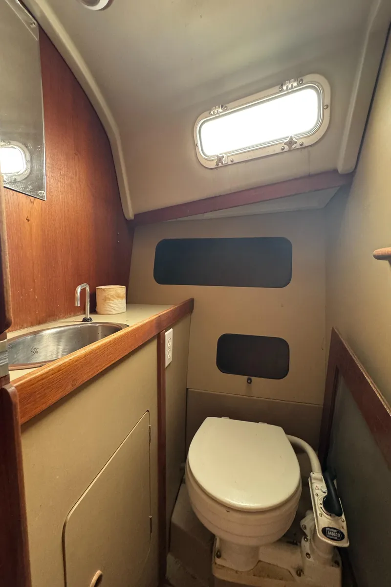 Slide: The Image of 1986 C&C 29 sailboat bathroom with sink, toilet, and porthole window. - 30