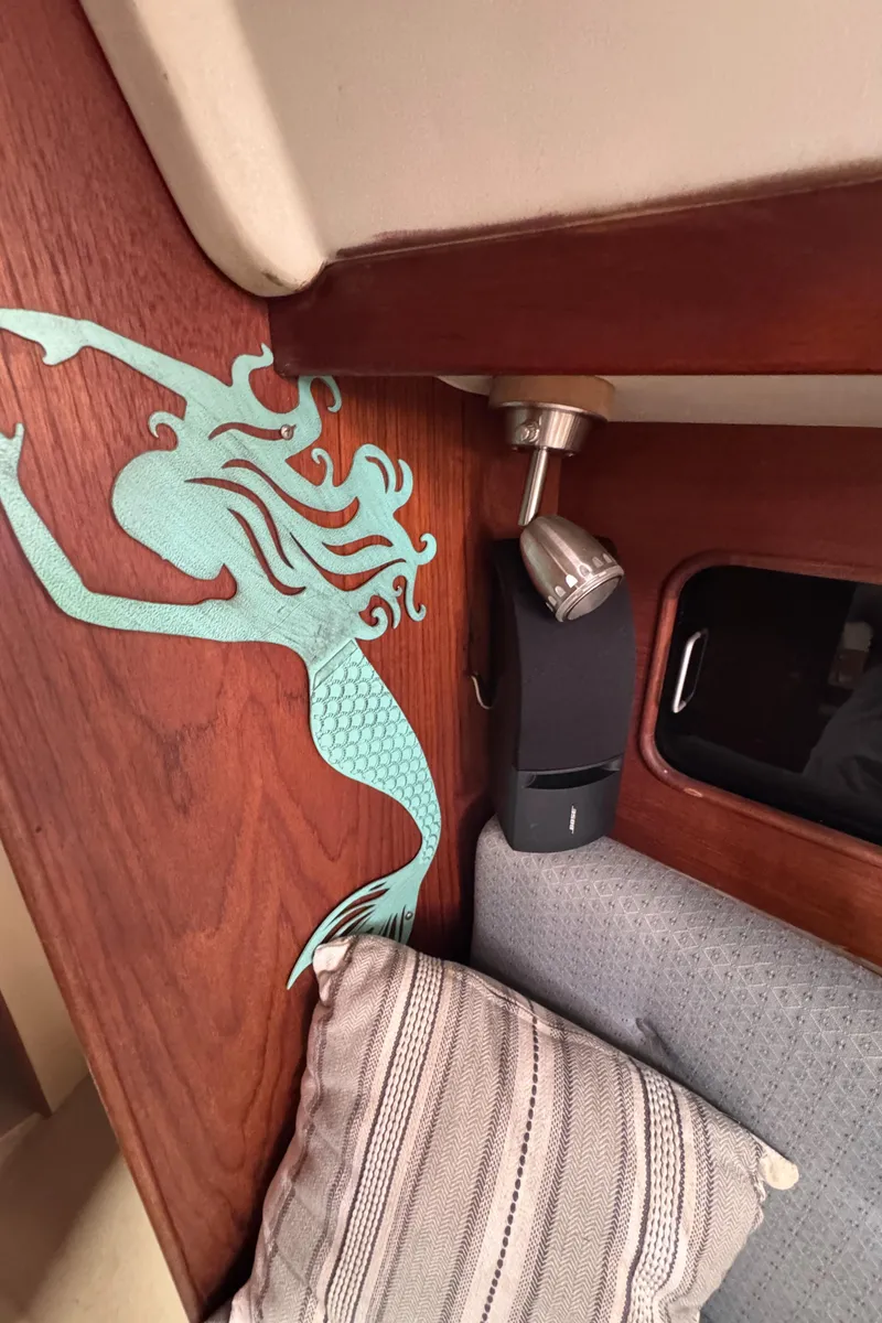 Slide: The Image of Interior of 1986 C&C 29 sailboat with mermaid wall art and cozy seating. - 32