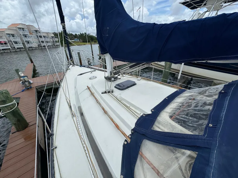 Slide: The Image of 1986 C&C 29 sailboat docked, featuring blue sail cover and marina backdrop. - 7