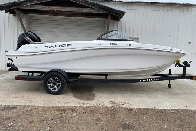 The Image of 2025 Tahoe 200 S boat on trailer, white exterior, parked outside a garage. - 0