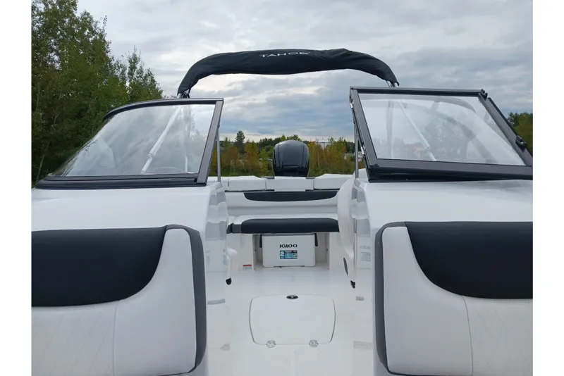 Slide: The Image of 2025 Tahoe 200 S boat interior with open windshield, black and white seating, and lush greenery backdrop. - 5