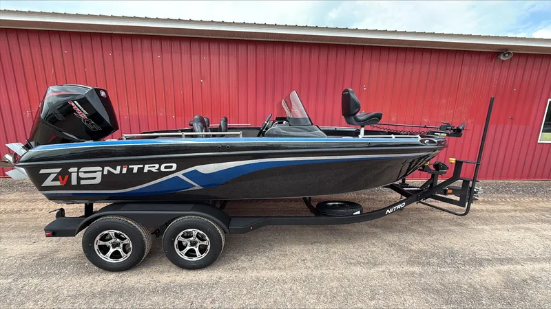 The Image of 2025 Nitro ZV19 boat on trailer, parked by a red building. - 0