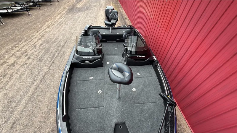 Slide: The Image of 2025 Nitro ZV19 boat with dual consoles and seating, parked beside a red wall. - 2