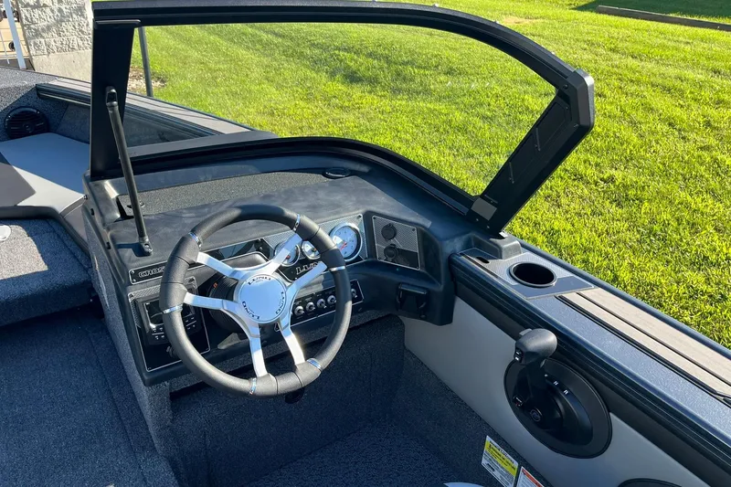 Slide: The Image of 2026 Lund 1875 Crossover XS boat cockpit with steering wheel and dashboard controls. - 12