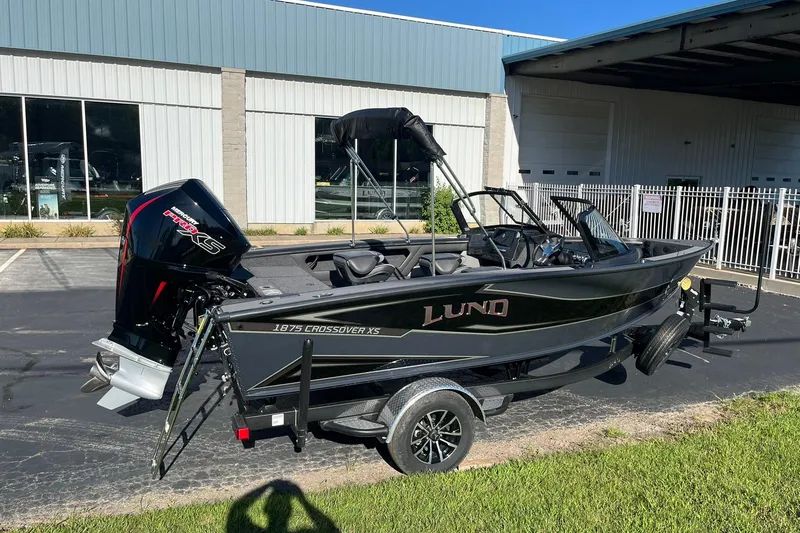Slide: The Image of 2026 Lund 1875 Crossover XS boat on trailer, parked outdoors. - 2