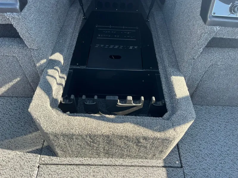 Slide: The Image of 2026 Lund 1875 Crossover XS boat interior with storage compartment, featuring gray carpeting. - 23