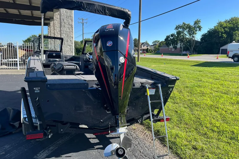 Slide: The Image of 2026 Lund 1875 Crossover XS boat with powerful outboard motor, parked on a sunny day. - 3