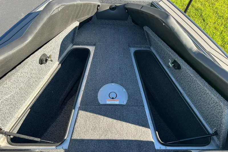 Slide: The Image of 2026 Lund 1875 Crossover XS boat interior with storage compartments and carpeted flooring. - 31