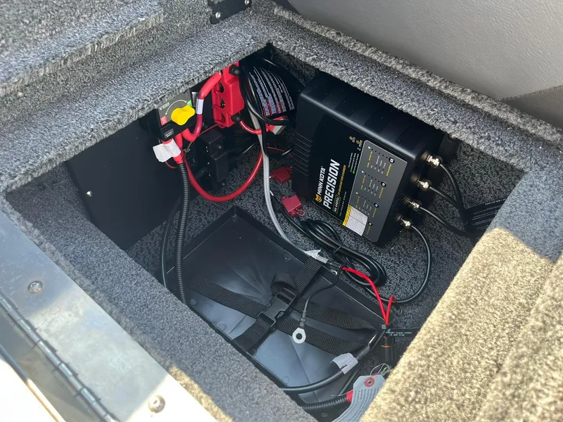 Slide: The Image of 2026 Lund 1875 Crossover XS battery compartment with wiring and charger. - 36