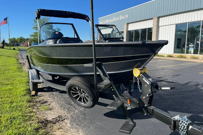 Slide: The Image of 2026 Lund 1875 Crossover XS boat on trailer at dealership, sunny day. - 5