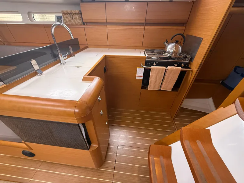Slide: The Image of 2011 Jeanneau 409 yacht kitchen with wooden cabinetry, stove, and sink. - 14