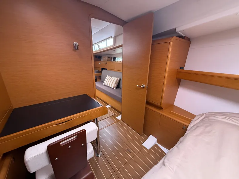 Slide: The Image of Interior of 2011 Jeanneau 409 yacht, featuring wood finish, desk, and cozy seating area. - 16