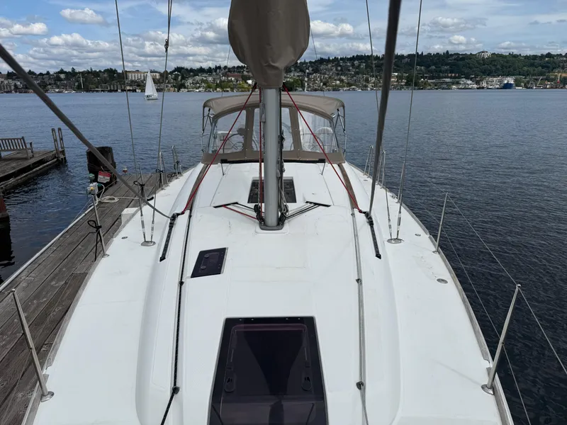 Slide: The Image of Sailboat Jeanneau 409, 2011 model, docked by a scenic waterfront with distant sailboats. - 23