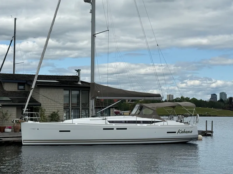Slide: The Image of Sailboat Jeanneau 409, 2011 model, docked by a waterfront house under cloudy skies. - 29