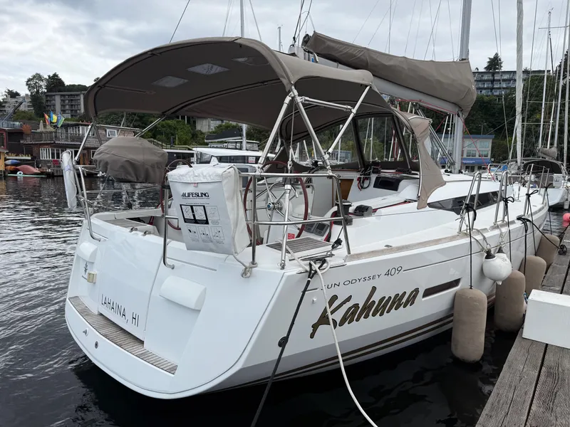 Slide: The Image of 2011 Jeanneau 409 sailboat docked, featuring a spacious deck and protective canopy. - 4