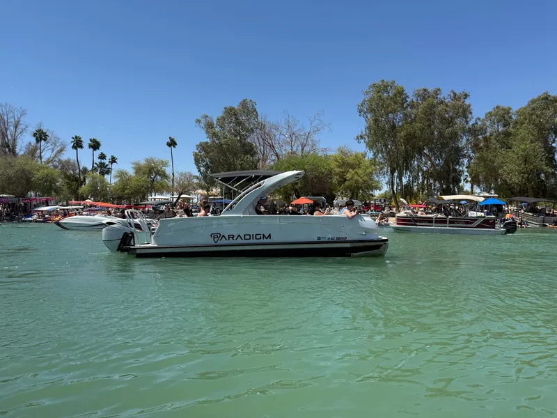 Slide: The Image of 2024 Paradigm 27SS boat on a sunny lake, surrounded by trees and other boats. - 4