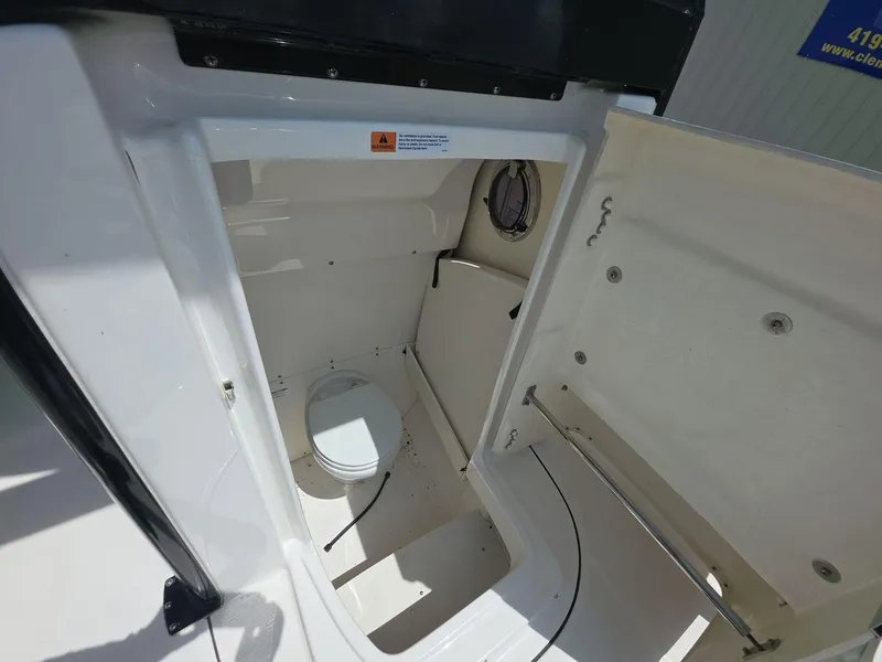 Slide: The Image of 2021 Robalo R272 Center Console boat interior with a compact marine toilet. - 11