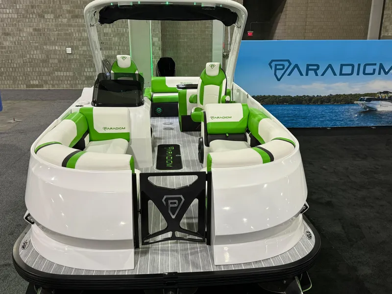 Slide: The Image of 2025 Paradigm 25SS boat with green and white seating on display indoors. - 2