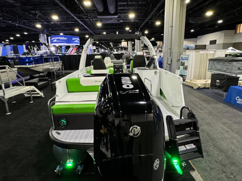 Slide: The Image of 2025 Paradigm 25SS boat with green seating and powerful outboard motor at a boat show. - 7