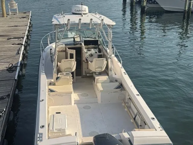 Slide: The Image of 1994 Grady-White Explorer 244 boat docked, featuring spacious deck and Garmin equipment. - 13
