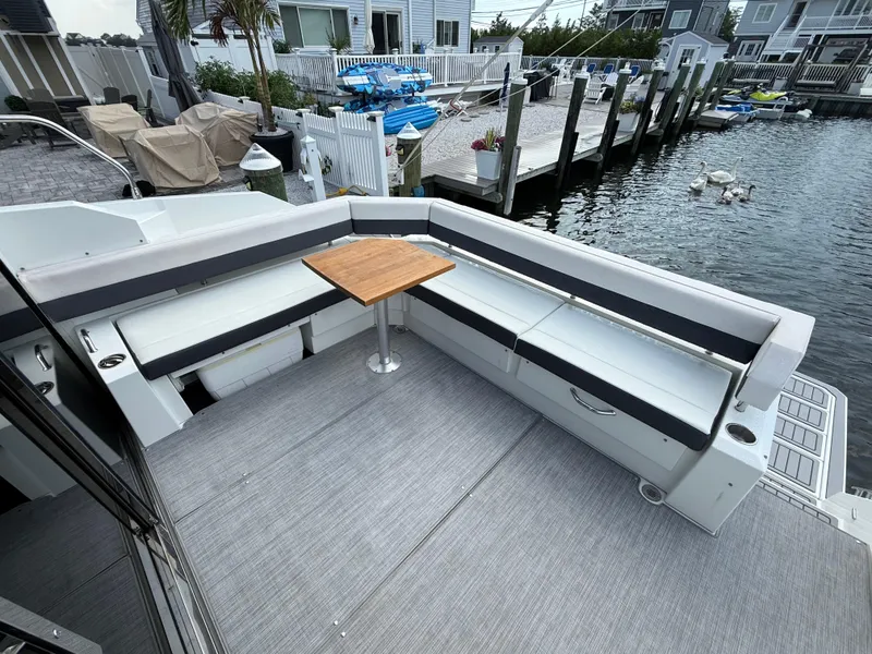 Slide: The Image of 2018 Cruisers Yachts 42 Cantius deck with seating and table by waterfront. - 15