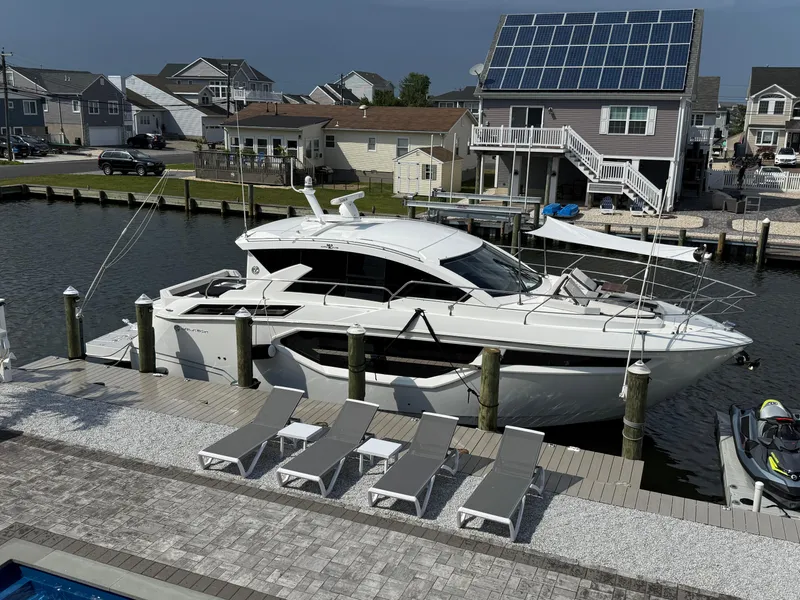 Slide: The Image of 2018 Cruisers Yachts 42 Cantius docked near waterfront homes with solar panels. - 6