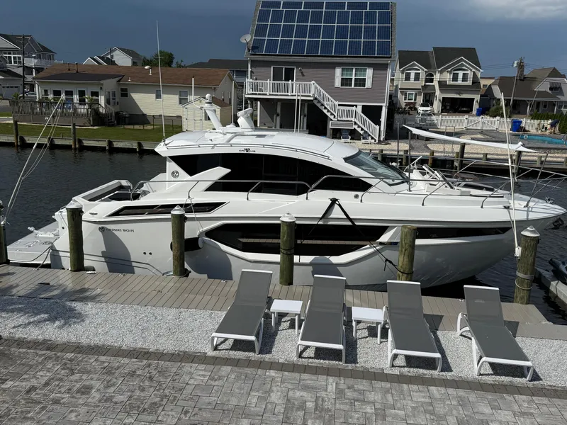Slide: The Image of 2018 Cruisers Yachts 42 Cantius docked near waterfront homes with solar panels. - 7